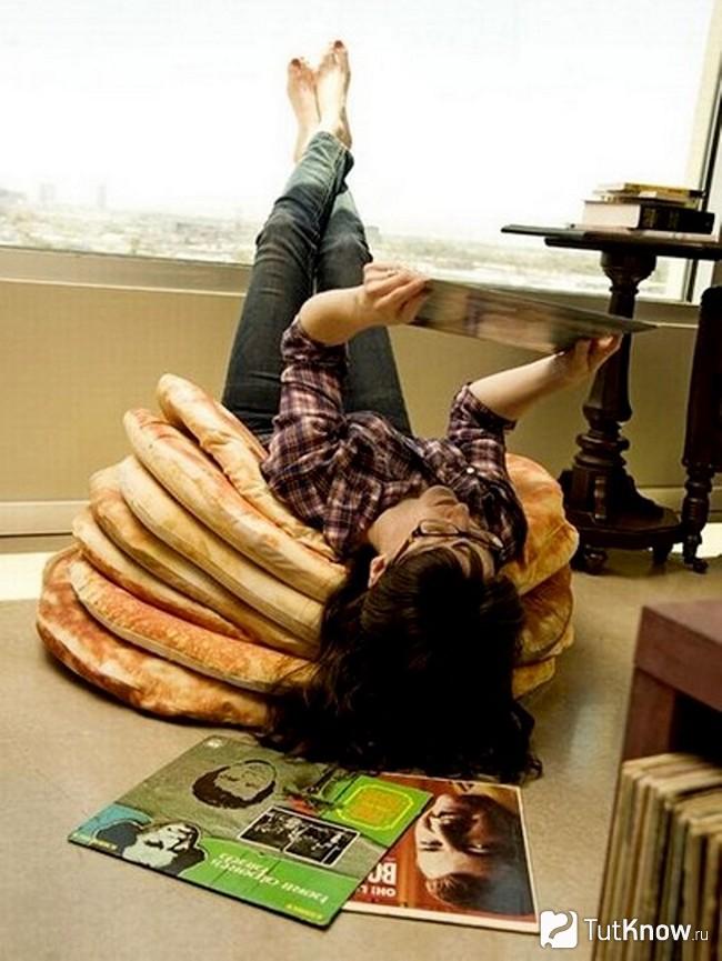 Девушка лежит на напольной подушке в виде блинов