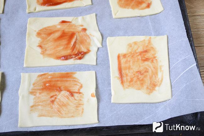 Кусочки слоёного теста смазаны кетчупом