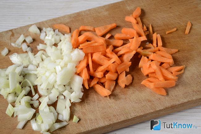 Лук и морковь нарезаны на кухонной доске