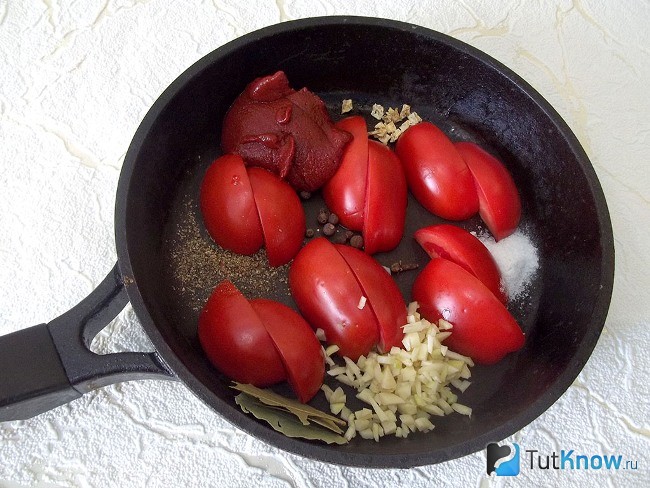 Нарезанные помидоры, томатная паста и специи лежат в сковороде