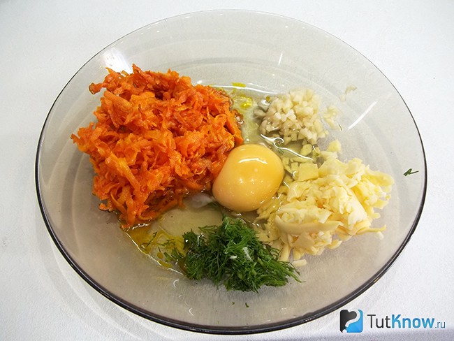 В тарелке соединенны продукты для начинки: морковь, сыр, яйцо, чеснок, укроп