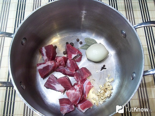 Мясо с луком и пряностями опущено в кастрюлю для варки бульона
