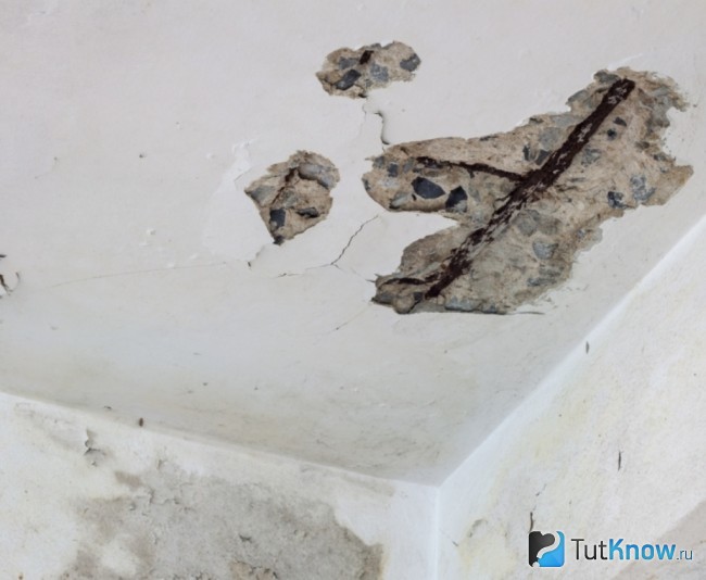 Требующий ремонта потолок с трещинами и выбоинами