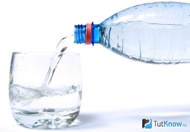 С бутылки воду наливают в стакан