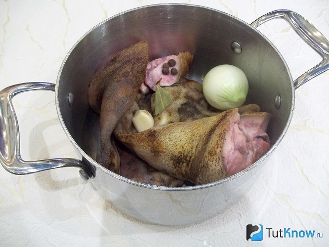 Подготовленное свиное ухо с луковицей и специями опущены в кастрюлю