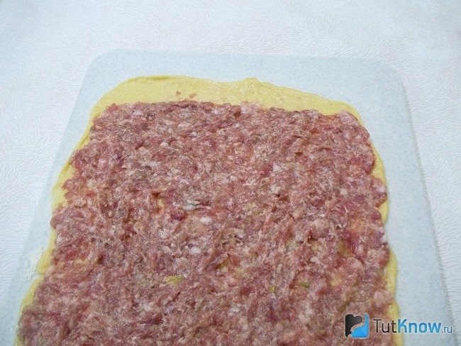 На тесто нанесена мясная начинка