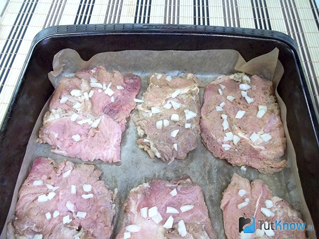 Мясо выложено на противень для запекания и присыпано чесноком