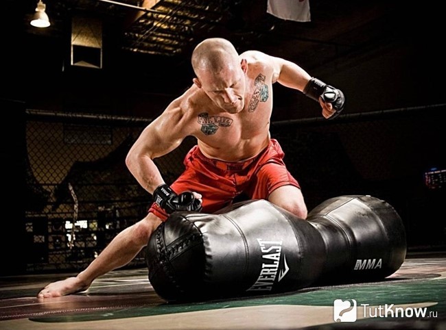 Спортсмен тренируется с боксерской грушей