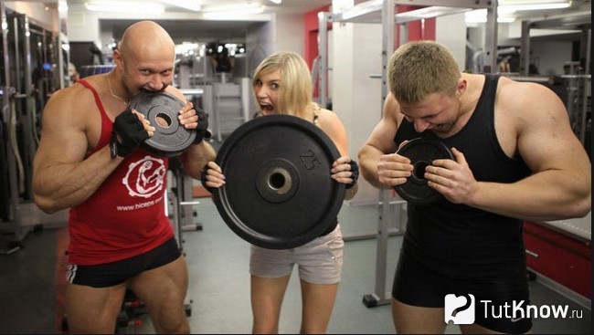 Спортсмены в зале едят блины для штанги