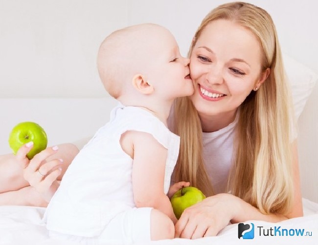 Девушка с ребенком держит яблоки