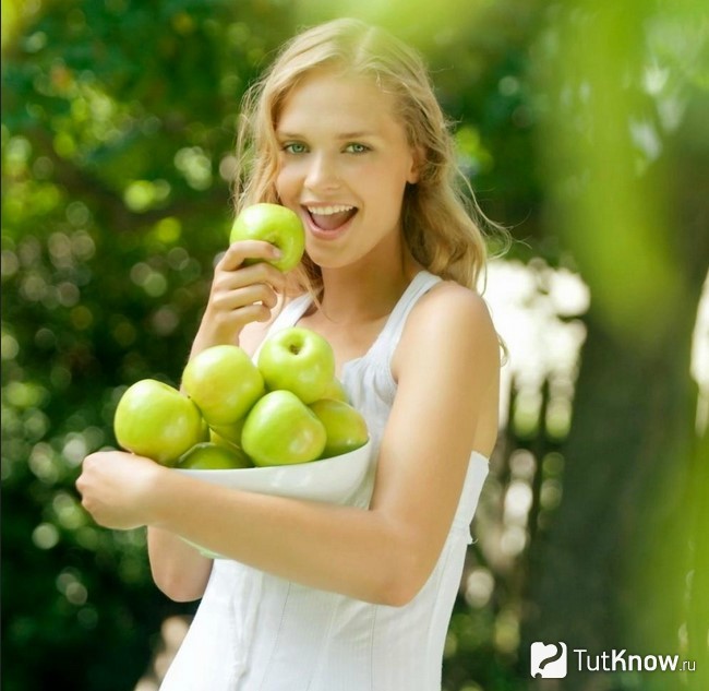 Девушка держит миску зеленых яблок