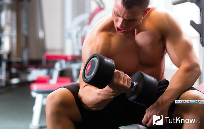 Спортсмен выполняет жим гантели сидя