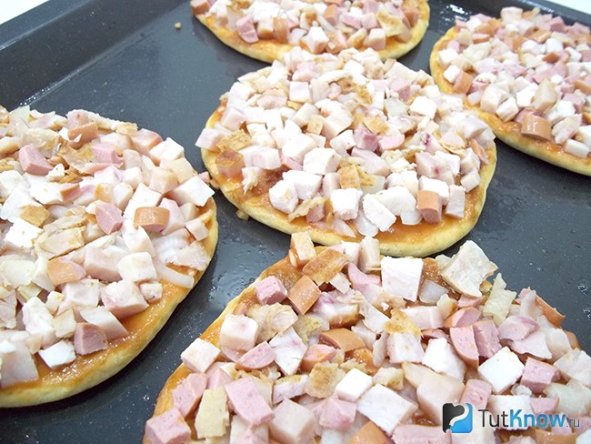 На тесто выложены мясные продукты