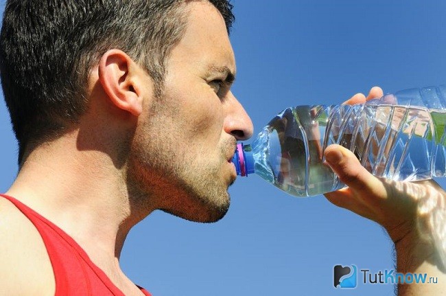 Спортсмен пьет воду из бутылки