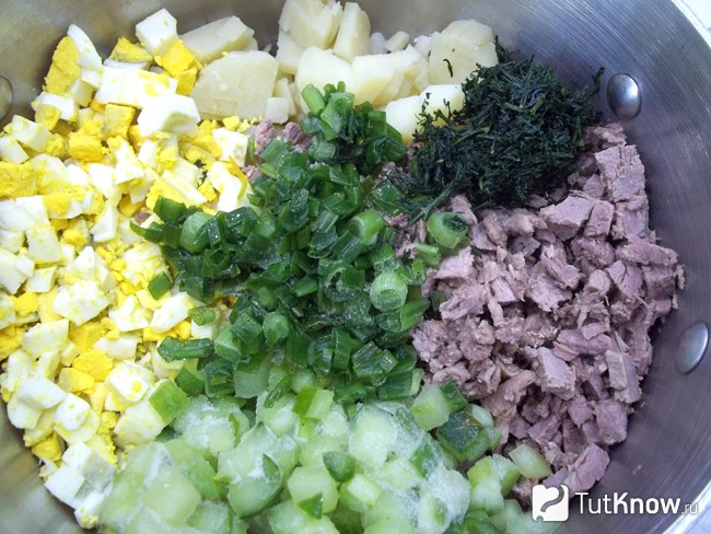 Продукты соединены в кастрюле и добавлены огурцы и зелень