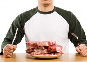 Мужчина за столом перед тарелкой с мясом