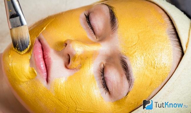 Нанесение маски из облепихового масла на лицо девушки
