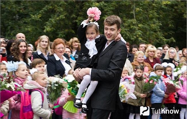 Выпускник несет первоклассницу на первом звонке