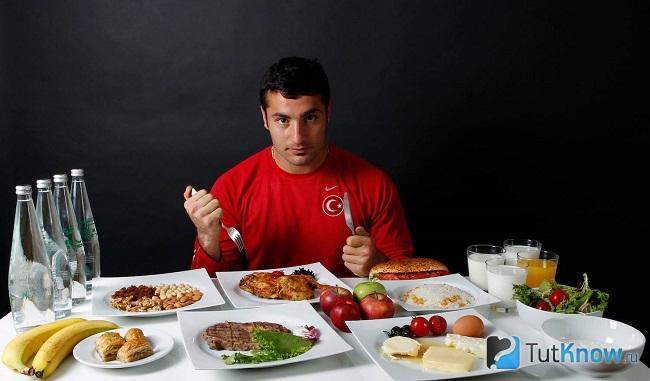 Спортсмен за столом готовится есть