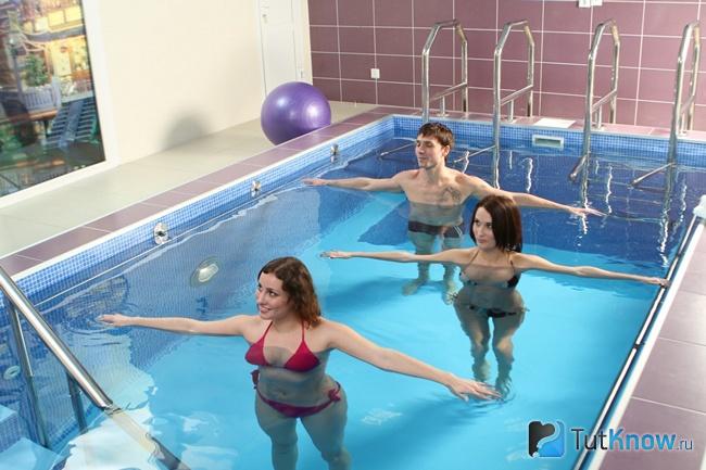Две девушки и парень тренируются в бассейне