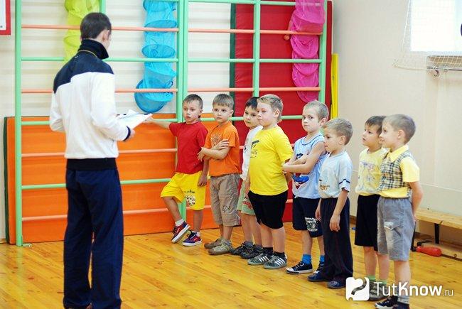 Учитель физкультуры стоит перед своими учениками