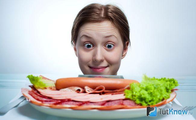 Тарелка с мясными изделиями перед девушкой