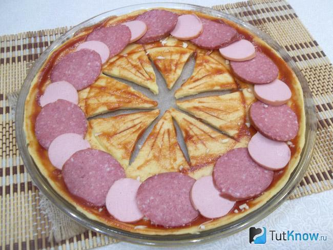 На тесто выложена колбаса