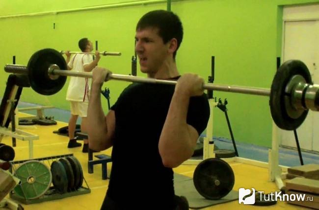 Начинающий спортсмен работает со штангой