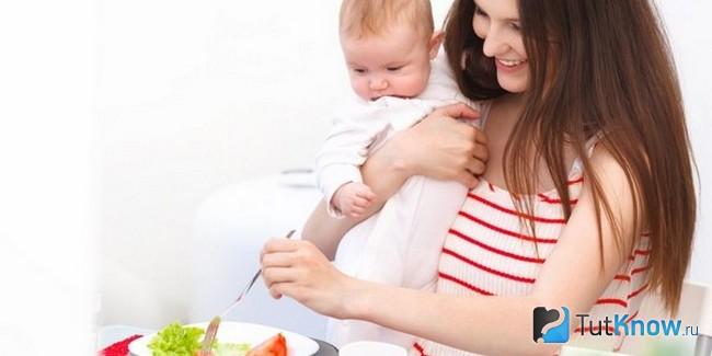 Девушка кушает салат, прижав к себе ребёнка