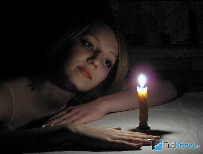 Девушка смотрит на горящую свечу