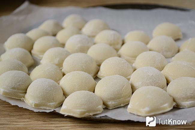 Слепленные пельмени на разделочной дощечке