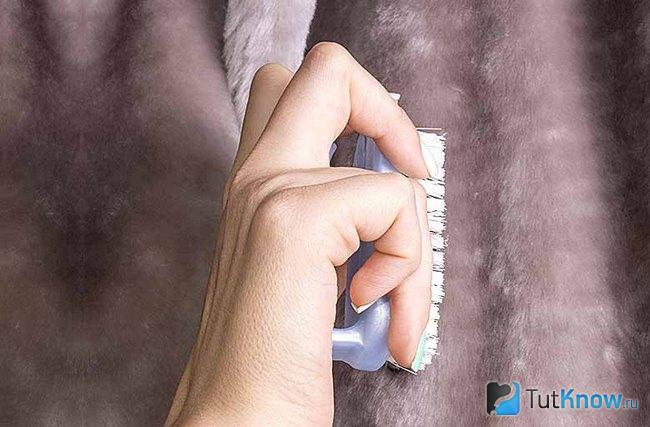 Процесс чистки меховой шубы щёткой