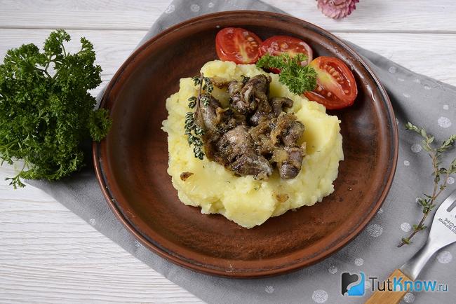 Готовые куриные сердечки с картофельным пюре на тарелке
