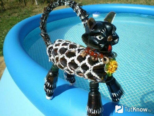 Чёрный кот из пластиковых бутылок возле бассейна