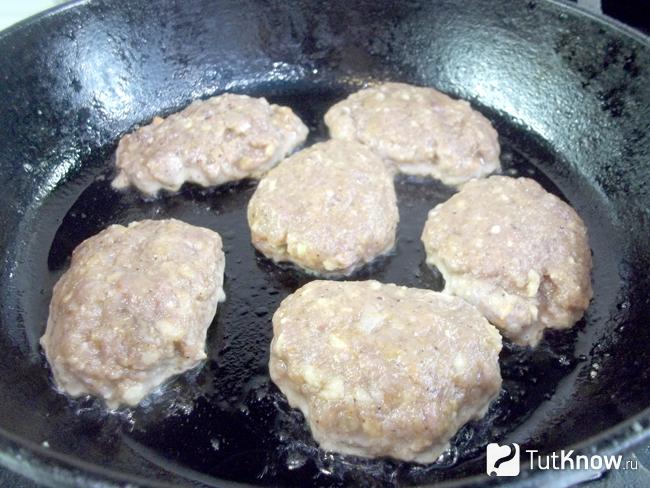 Оладьи из мяса, овощей и рыбной икры жарятся на сковороде