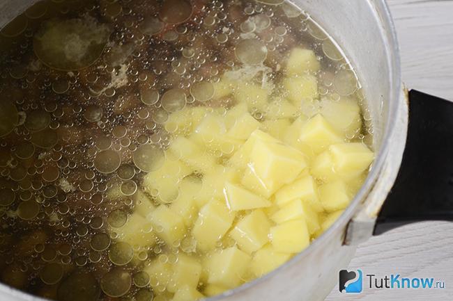 Картофель, нарезанный кубиками, добавлен в кастрюлю с фасолью