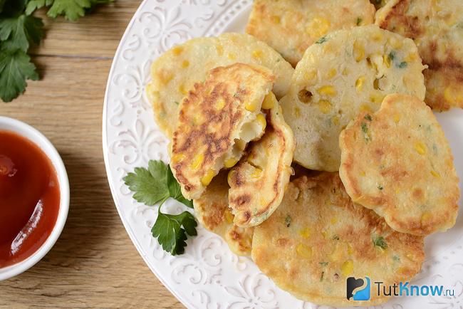 Закусочные оладьи с консервированной кукурузой лежат на тарелке