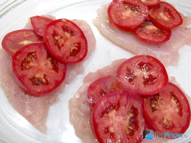 На куриное филе выложены помидоры нарезаны кольцами