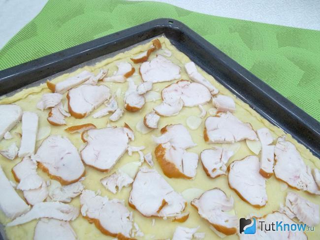 На тесто разложена ветчина нарезана тонкими слайчсами