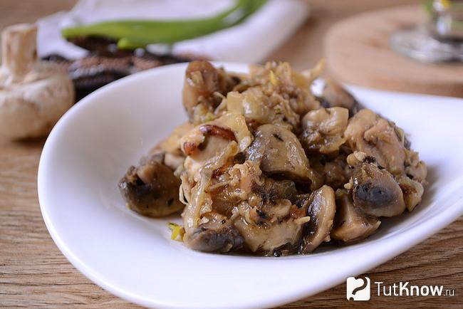 Жареные куриные бёдрышки с грибами и луком крупным планом