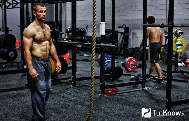 Спортивный парень стоит перед свисающим канатом