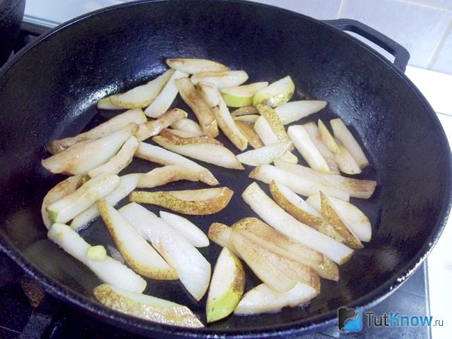 Яблоки и груши жарятся в сковороде на растительном масле