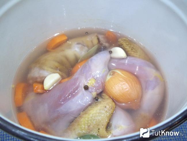 Курица, свиное копыто и нарезанные овощи сложены в кастрюлю и залиты водой