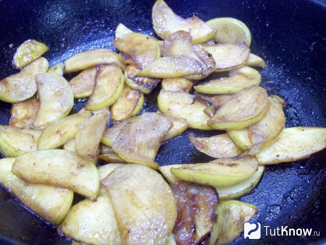 Яблоки приправлены сахаром и корицей и жарятся в сковороде