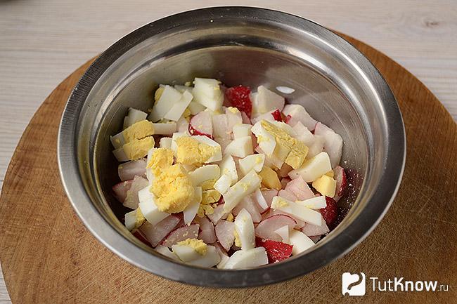 Нарезанные варёные яйца добавлены в миску с редисом