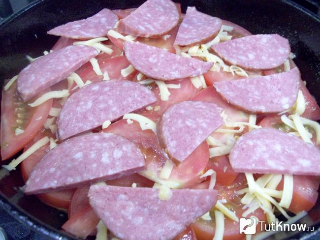 помидоры присыпаны сырной стружкой и сверху выложена нарезанная кольцами колбаса