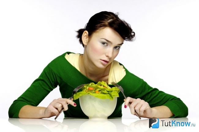 Девушка сидит перед тарелкой с салатом