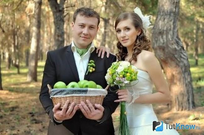 Жених держит в руках корзинку с яблоками