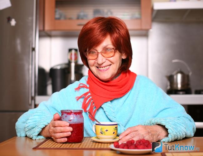 Женщина пьет чай с малиновым джемом