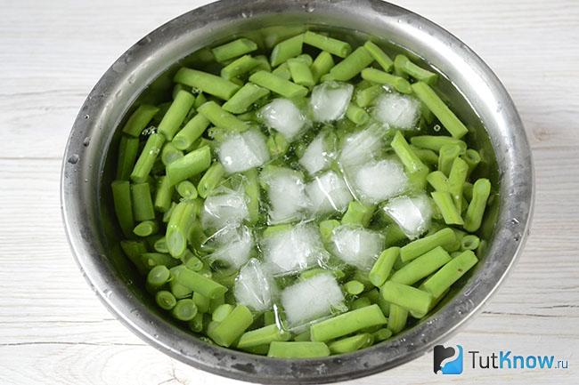 Стручковая фасоль в миске с водой и кубиками льда